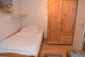A small bedroom with a single bed, a wooden wardrobe, and a small table. - Holiday Home by the Baltic Sea with Terrace (Ostseebad Rerik)