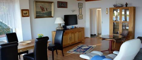 Un salon avec un plafond en bois, un téléviseur, un meuble, une table à manger et un canapé.