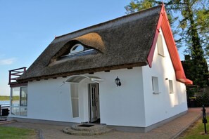 A small white building with a thatched roof and a red chimney.