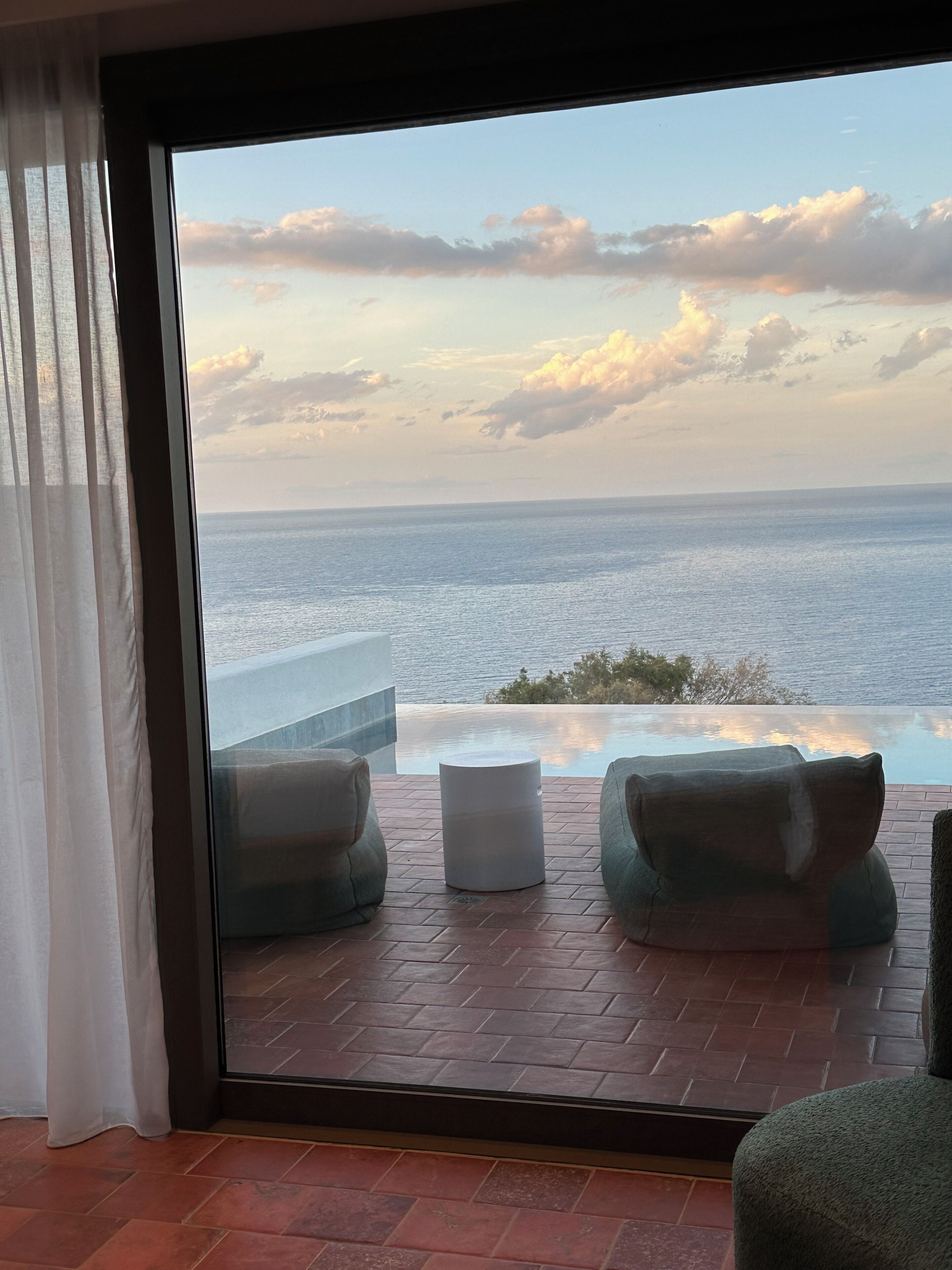 A room with a view of the ocean, a glass door, and a tiled floor.