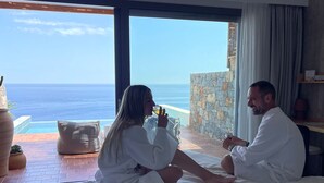 A couple sitting on a bed with a view of the ocean. - Maison Meltem (Malevizi)