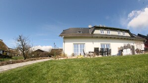Ein zweistöckiges Haus mit großem Vorgarten, einem Weg zum Eingang und blauem Himmel.