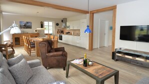 Ein modernes Wohnzimmer mit einer Couch, einem Couchtisch mit einer Flasche und einem Fernseher.