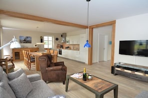 Ein modernes Wohnzimmer mit einer Couch, einem Couchtisch mit einer Flasche und einem Fernseher.