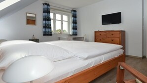 Ein Schlafzimmer mit Bett, Schreibtisch, Stuhl, Kommode und Fernseher.