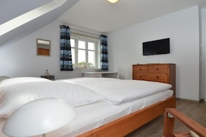 Ein Schlafzimmer mit Bett, Schreibtisch, Stuhl, Kommode und Fernseher.