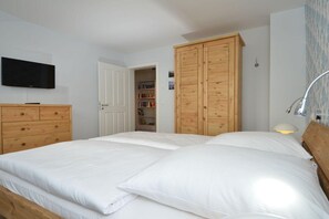 A bedroom with a double bed, wooden wardrobe, a television, and a bookshelf.