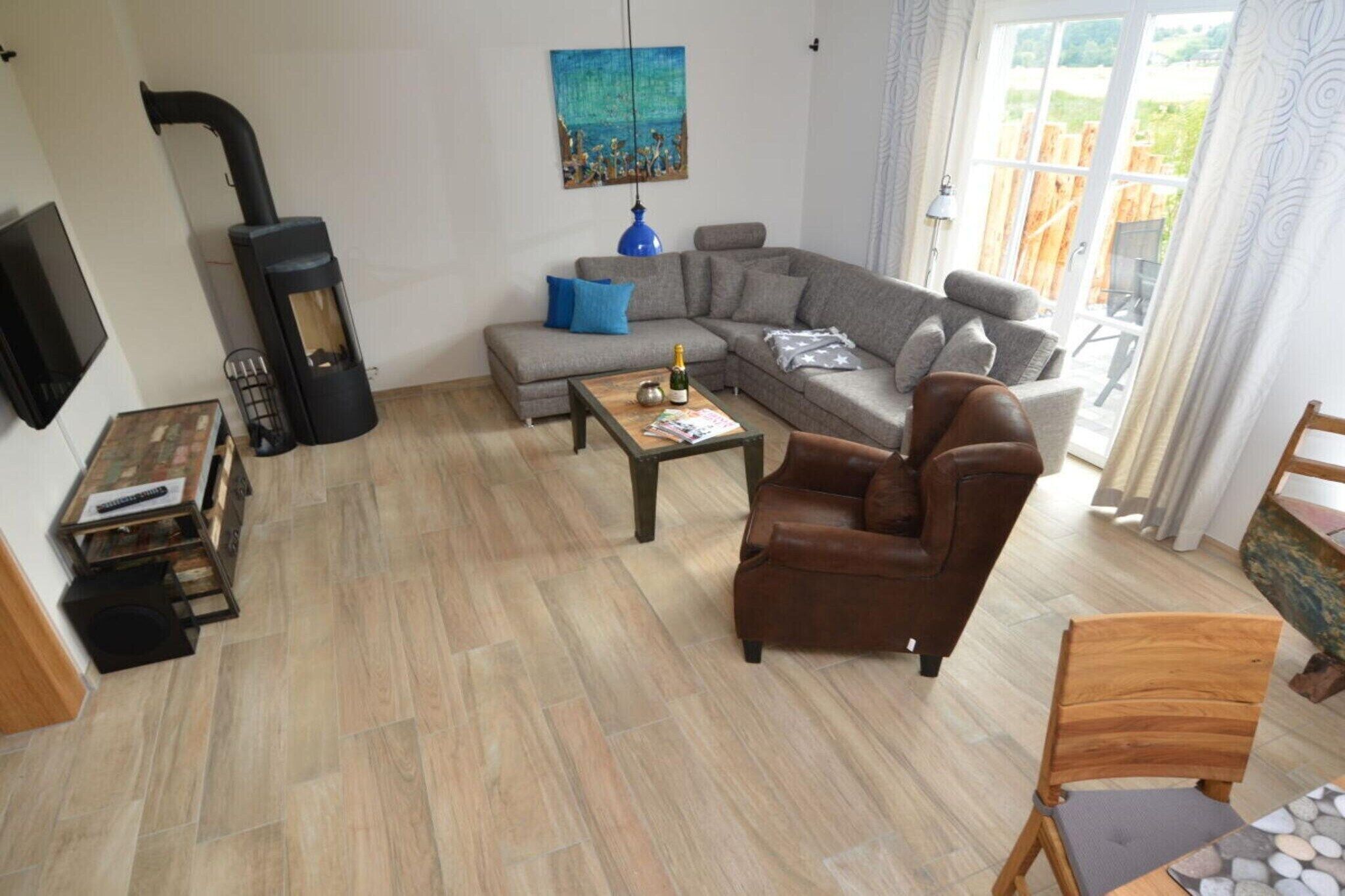 Uma sala de estar com sofá, poltrona, mesa de centro e lareira.