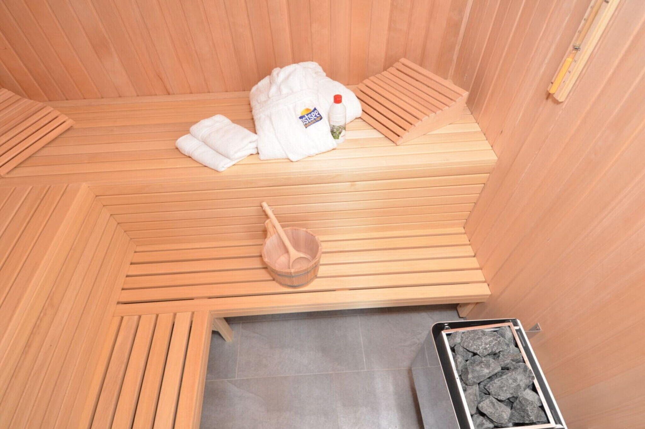 Een sauna met een houten bank, een handdoek, een fles en een houten schep.