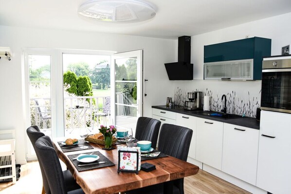 A modern kitchen with white cabinets, a black countertop, and a built-in oven.