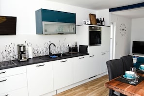 A modern kitchen with white cabinets, a black countertop, and a blue accent wall.