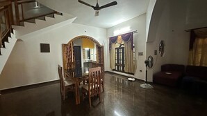 A spacious living room with a dining area, a staircase, and a ceiling fan.