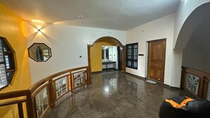 A spacious hallway with a polished floor, a wooden door, and a black bean bag on the right.