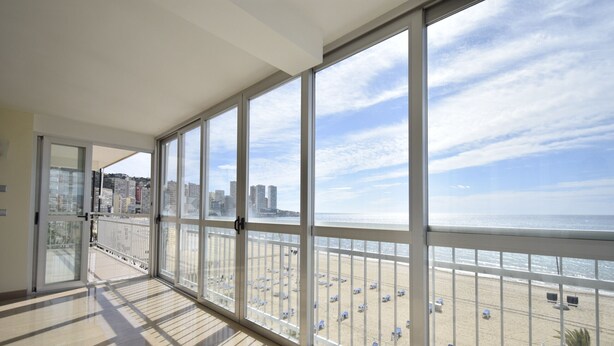 A spacious balcony with large windows overlooking a beach and cityscape. - MAR Y VENT - SEA VIEW (3 BEDROOMS) (Benidorm)