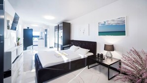 Een moderne hotelkamer met een groot bed, een nachtkastje met een lamp en uitzicht op de zee.