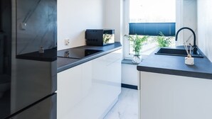 Een moderne keuken met witte kastjes, zwarte aanrechtbladen en een ingebouwde kookplaat.