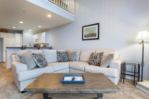 A modern living room with a sectional sofa, a coffee table, and a framed picture on the wall.