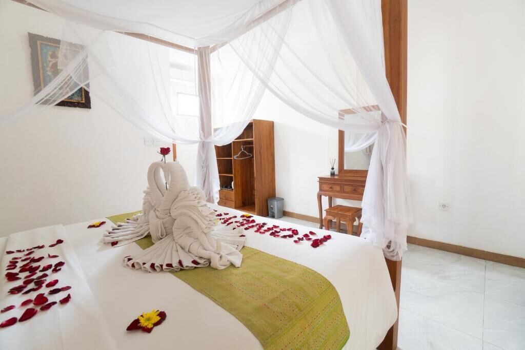 A bedroom with a canopy bed, a wooden wardrobe, a desk, and a chair.