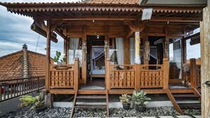 Una casa de madera con un porche, escalones que llevan a una puerta y macetas con plantas.