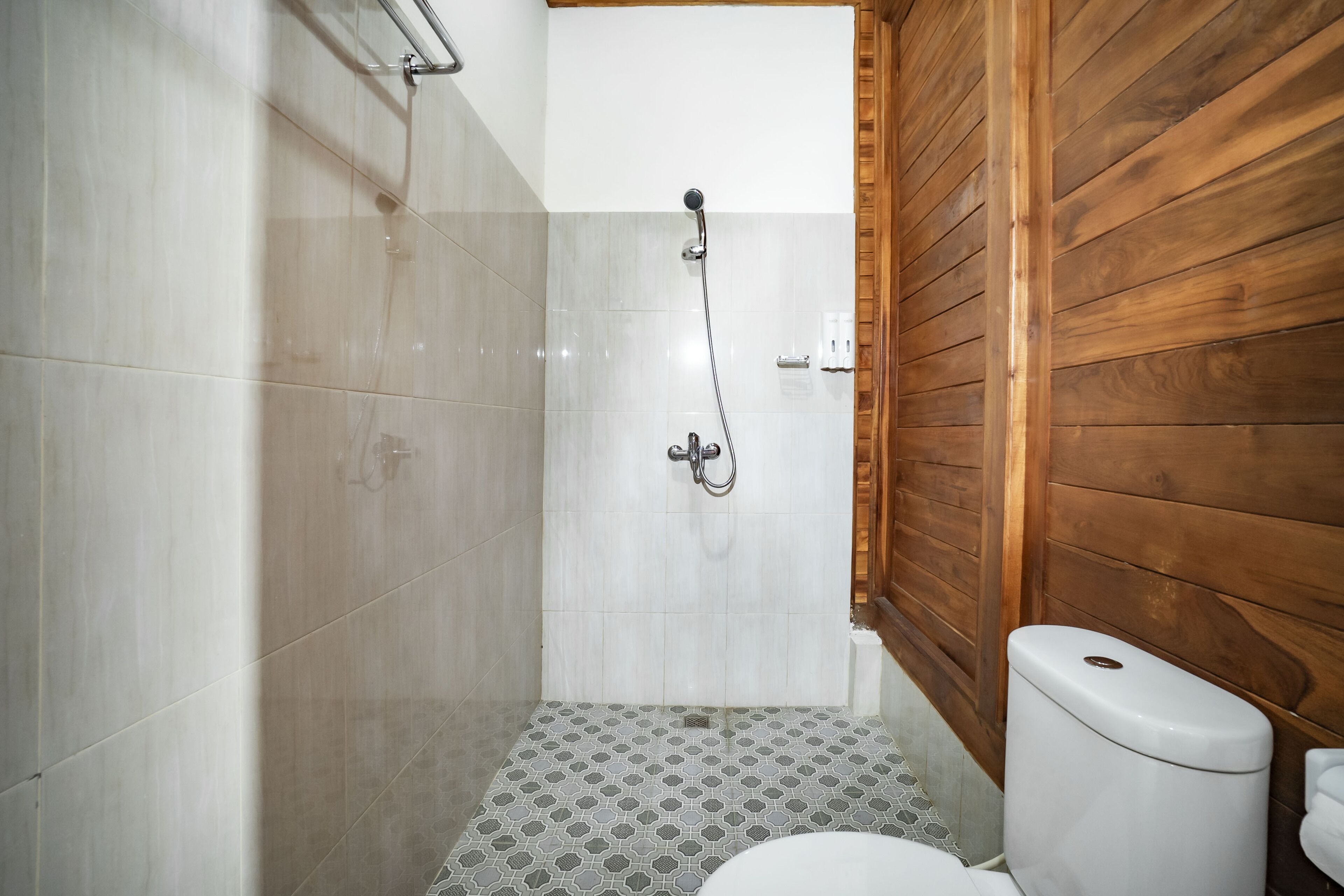 Un baño pequeño con ducha, inodoro y suelo de baldosas.