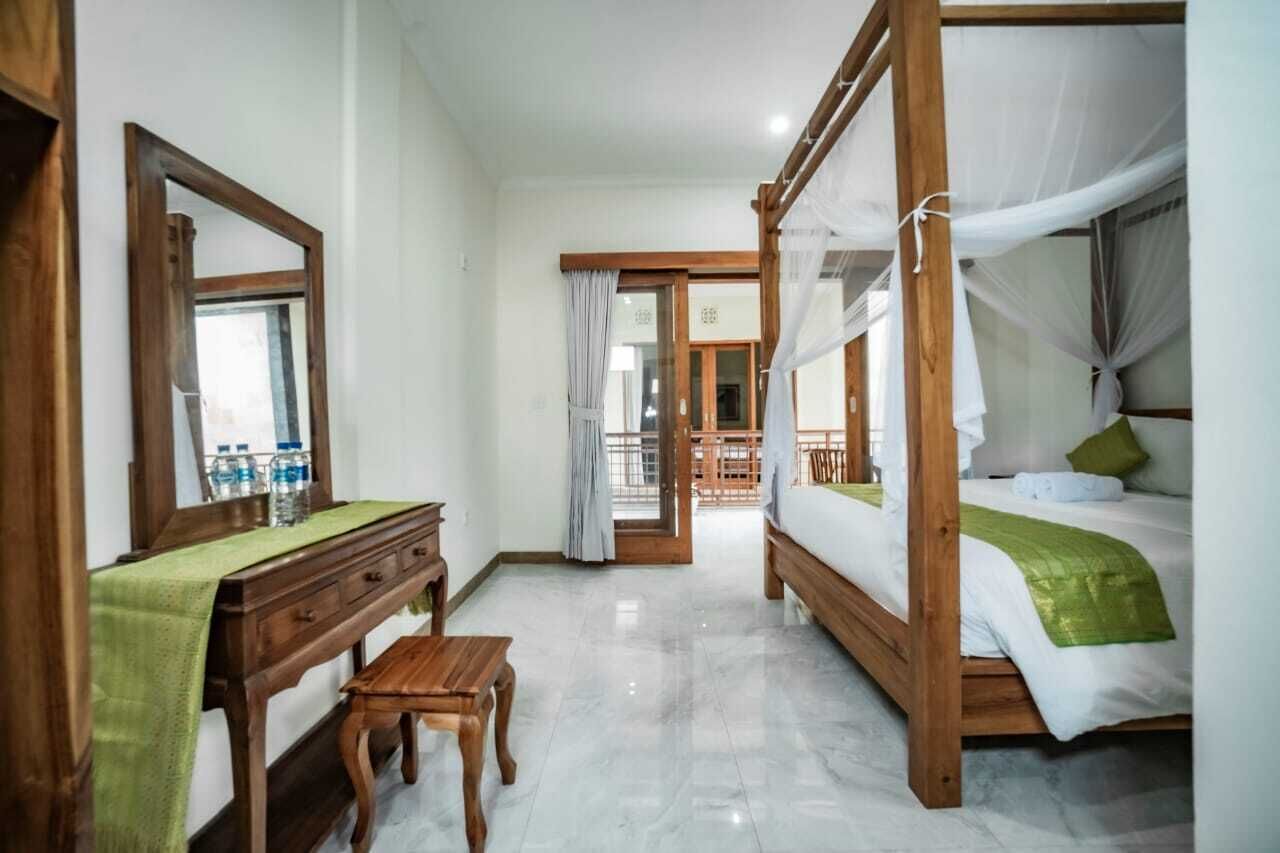 A bedroom with a wooden bed, a nightstand, a mirror, and a desk with a green cloth.