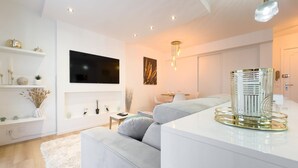A modern living room with a flat-screen TV, a sofa, a coffee table, and a decorative glass vase.