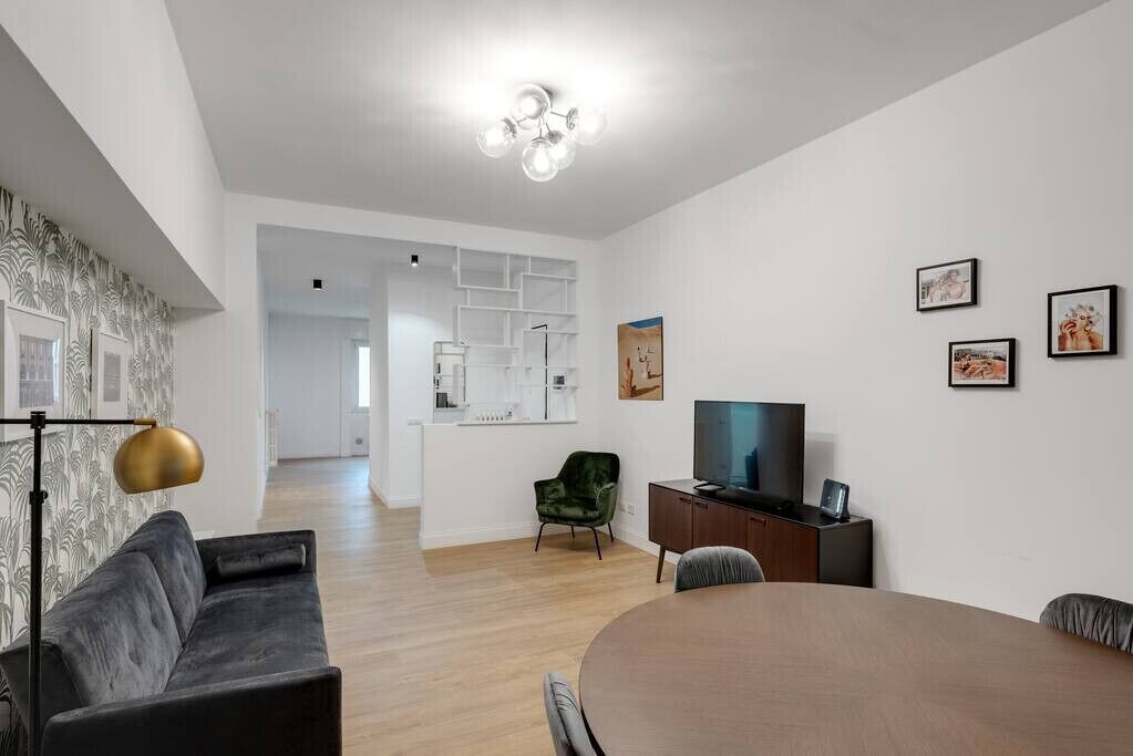 En moderne stue med en sofa, et spisebord, et fjernsyn og en grøn stol.