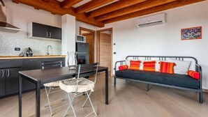 A compact kitchen with modern appliances, a dining table with chairs, and a sofa with colorful cushions. - Amazing flat with a view and terrace on Navigli by Easylife (Milano)