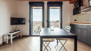 A modern kitchen with a black countertop, a dining table with a vase, and a TV on the wall. - Amazing flat with a view and terrace on Navigli by Easylife (Milano)