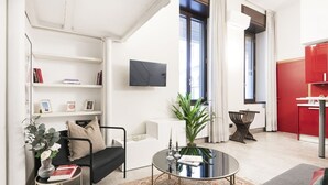 A modern living room with a sofa, coffee table, and a flat-screen TV mounted on the wall. - Easylife - Cozy studio in Via Torino, perfect location to visit the city (Milano)