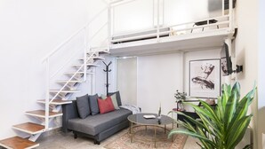 A modern living room with a grey sofa, a coffee table, a staircase, and a plant. - Easylife - Cozy studio in Via Torino, perfect location to visit the city (Milano)
