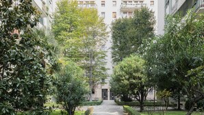 A pathway leading to a building with a gated entrance, surrounded by lush greenery and trees. - Easylife - Elegance and Comfort in the Isola area (Milano)