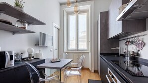 Una cocina moderna con comedor, televisor y ventana con persianas.