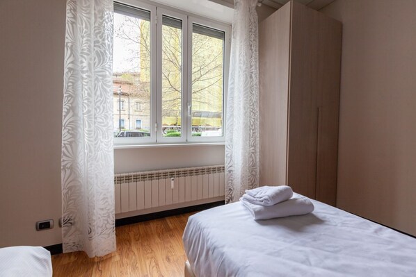 Une chambre à coucher avec un lit, un radiateur et une fenêtre avec des rideaux.