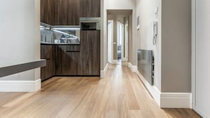 A modern kitchen with dark wood cabinets, stainless steel appliances, and a wooden floor. - Easylife - Luxury and Comfort in Brera district (Milano)