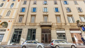 A multi-story building with a central entrance, large windows, and a visible storefront on the ground floor. - Easylife - Luxury and Comfort in Brera district (Milano)