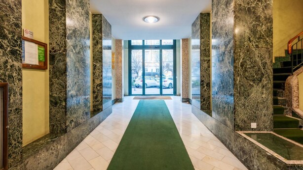 A marble-floored hallway with a green carpet leading to a glass door entrance. - Easylife-Spacious and comfortable apartment in the Duomo (Milano)
