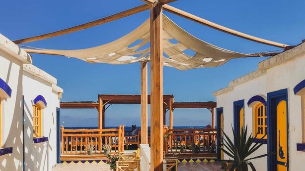 A rooftop terrace with a wooden pergola, potted plants, and a view of the sea. - Neptune Dahab Hotel (Dahab)