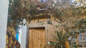 A wooden door with a metal handle, a wooden staircase with a railing, and a potted plant on the right. - Neptune Dahab Hotel (Dahab)