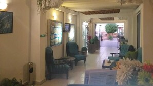 A hotel lobby with a wooden ceiling, green armchairs, a reception desk, and a large potted plant. - Neptune Dahab Hotel (Dahab)