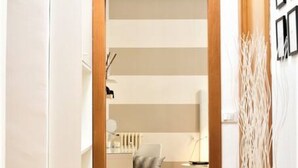 A modern room with a wooden door, a chair, a small table, and a decorative plant.