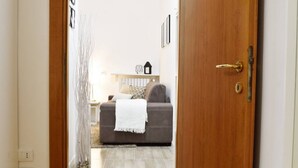 A doorway leading to a living room with a sofa, a lamp, and a decorative vase.