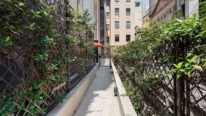 A narrow alleyway flanked by buildings with a metal fence on one side and a gate in the center. - Amazing apartment in Duomo by Easylife (Milano)