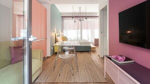 A modern hotel room with a glass partition, a bed, a TV, and a dining area with a table and chairs. - Amazing apartment in Duomo by Easylife (Milano)