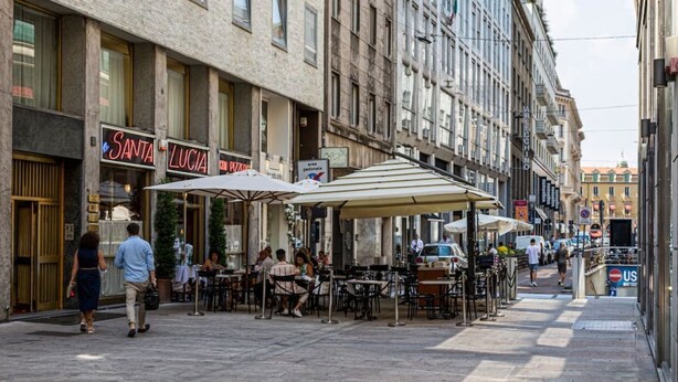 An outdoor café with tables and umbrellas, a sign for 'Santa Lucia' restaurant, and a 'US' parking sign. - Amazing apartment in Duomo by Easylife (Milano)