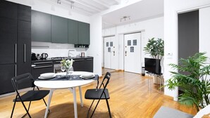 Una cocina moderna con armarios oscuros, una mesa de comedor con sillas y un televisor en la sala.