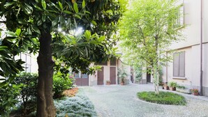 Un patio con un sendero de grava, rodeado de plantas y árboles en macetas.