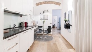 A modern kitchen with white cabinets, a black countertop, and a dining area with a round table and chairs.