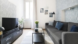 A modern living room with a sofa, a coffee table, a TV, and a radiator.
