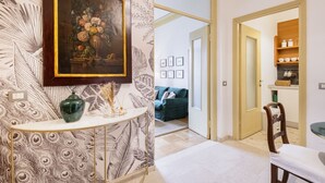 A room with a peacock feather wallpaper, a framed floral painting, a green vase, and a wooden chair. - Easylife - Classy abode in the Conciliazione area (Milano)